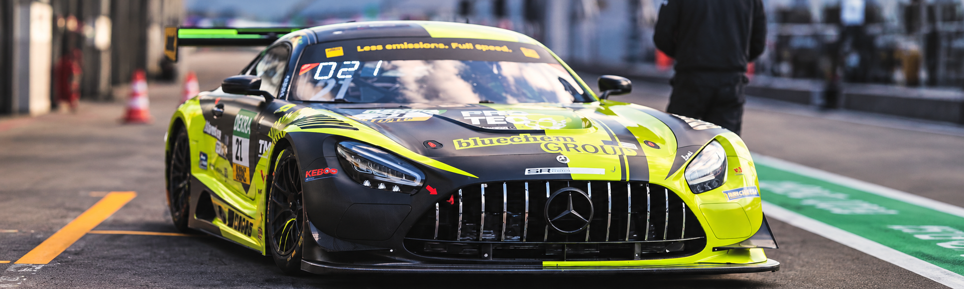 Mașină de curse Mercedes-AMG GT, în culori negru și verde neon, staționată pe linia boxelor
